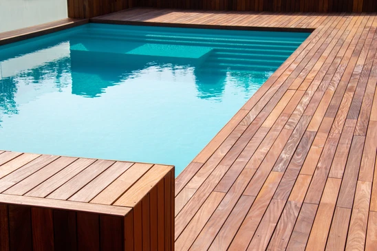 Aménagement paysager extérieur moderne avec terrasse en bois composite, jardin minéral composé de galets anthracite, arbustes verts taillés en boules, graminées ornementales et bambous